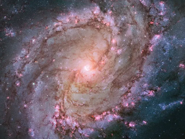 A large spiral galaxy stretches across the image, with a bright core surrounded by large spiral arms laced through with dark dust and purple and pink regions of star formation.