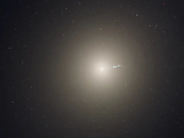 A bright, yellowish galaxy core shines near the center, with a faint jet of material ejecting toward the right.