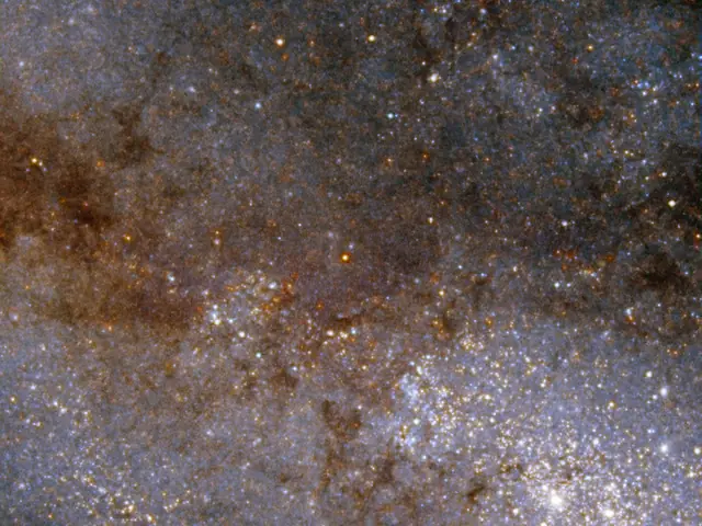 Bright stars scatter across the field of view, more closely concentrated at the lower right. Dark brown lanes of dust spread throughout the view.